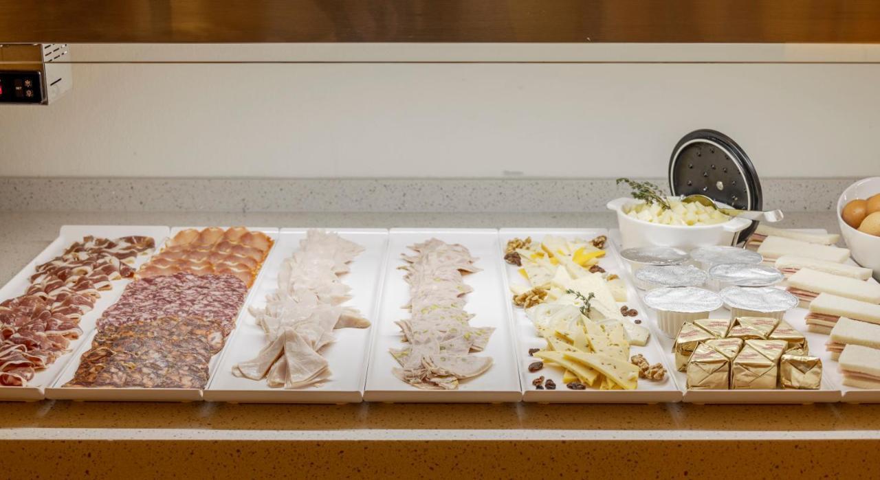 伊露尼翁梅里达宫酒店 外观 照片 The photo displays a variety of food items arranged on a counter. From left to right, there appears to be several types of sliced meats, possibly including salami and ham. Next, there are slices of a lighter-colored meat, likely turkey or chicken. Fo