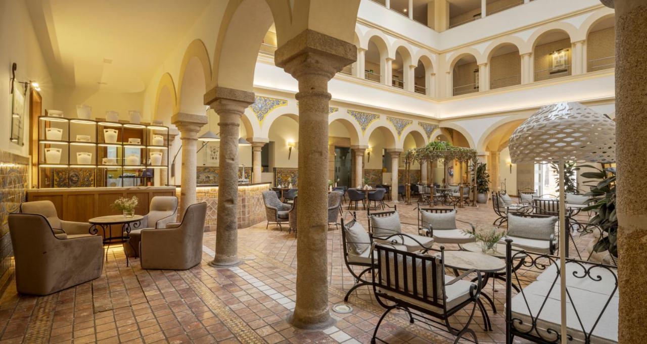 伊露尼翁梅里达宫酒店 外观 照片 The photo shows a spacious and elegantly designed interior of a hotel or a public venue. It features a courtyard with several arches and columns, giving it an airy and sophisticated feel. There are comfortable seating areas with armchairs and tables 